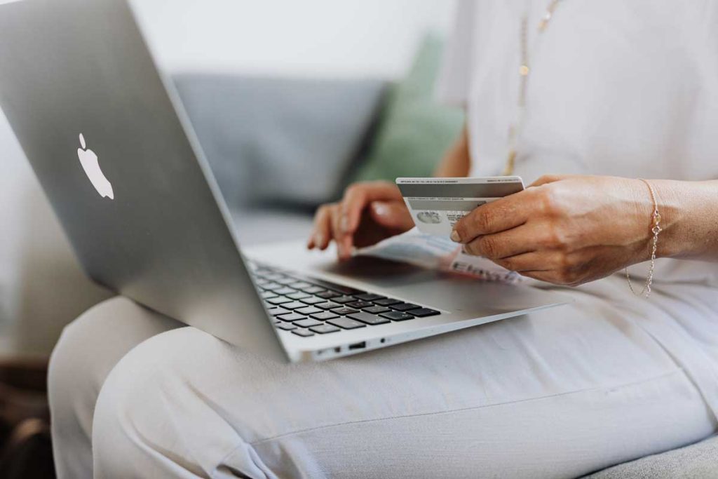 Image of a woman using their laptop and credit card to make purchases online.